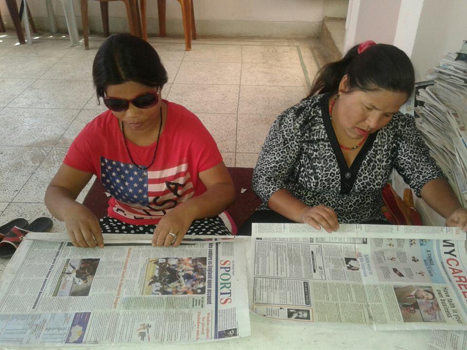 Two visually impaired women making bags from used newspapers. Prayatna Nepal helped them acquired this skill.