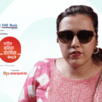 A medium shot of Sarita Lamichhane, a woman with short dark hair wearing large brown sunglasses and a pink and white patterned kurta. Behind her is a graphic with the "Global IME Bank" and "Online Khabar" logos, the number "40" in a stylized red and black design, and text in Nepali.