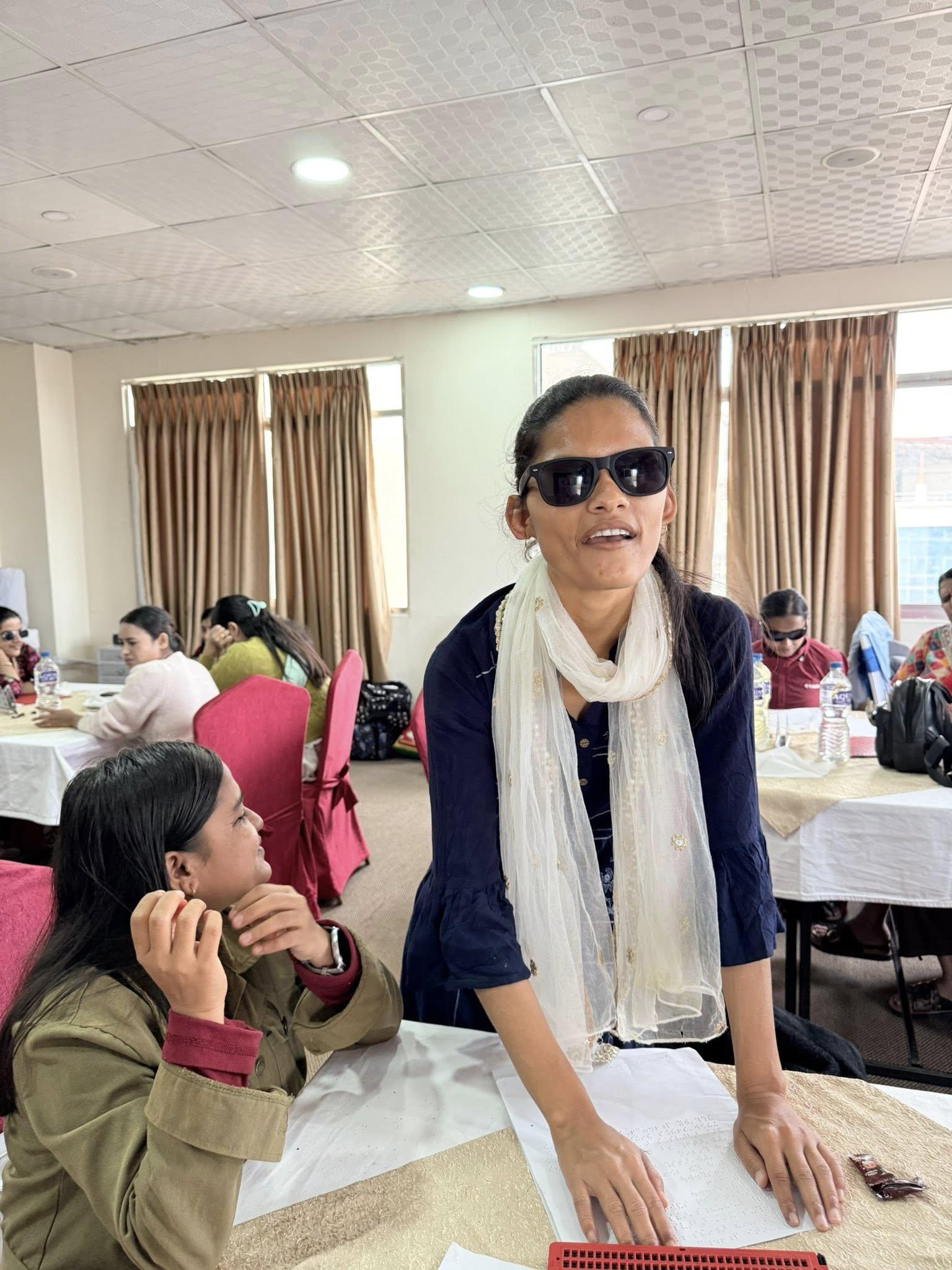 A girl in room full of other people presenting wearing white swal in a room.