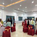 Participants (girls and women with visual impairment) are seen standing in their designated group table and holding hands in a circle. In this picture, participants in three tables are seem doing so