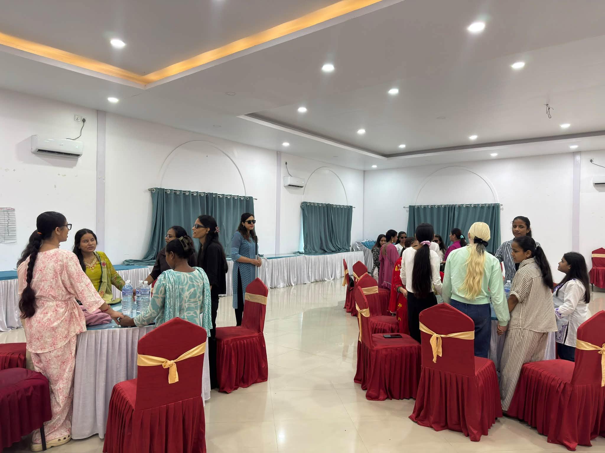 Participants (girls and women with visual impairment) are seen standing in their designated group table and holding hands in a circle. In this picture, participants in three tables are seem doing so